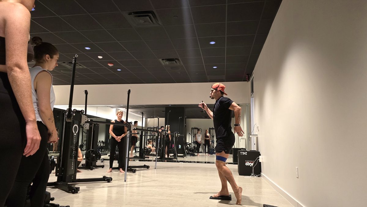 A Kinetic Blueprint coach demonstrating a single-leg gait pattern to a class inside the studio